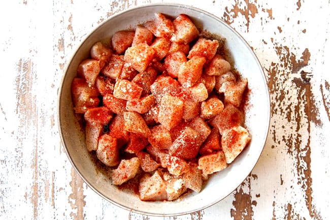 showing how to make creamy chicken and rice recipe by seasoning chicken in a bowl with paprika, salt and pepper