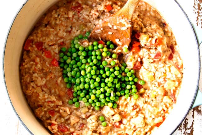showing how to make creamy chicken and rice recipe by stirring in peas once the rice is tender