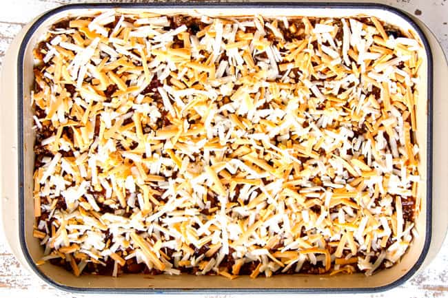 showing how to make Mexican Lasagna recipe by finishing layers with one layer of meat sauce and shredded cheeee