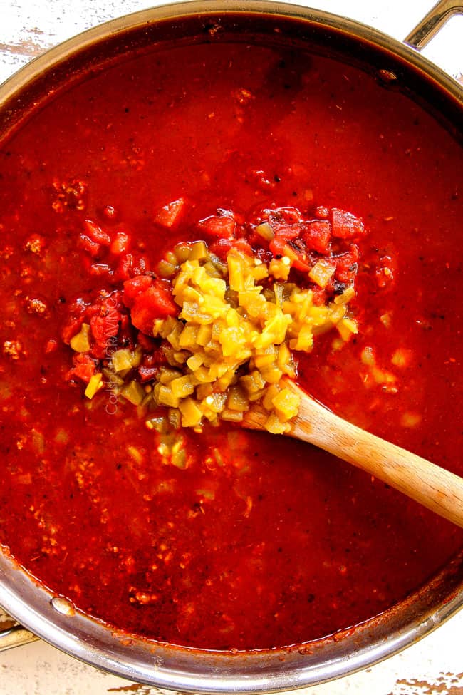 showing how to make Mexican Lasagna recipe by adding chicken broth, green chilies and diced tomatoes to ground beef