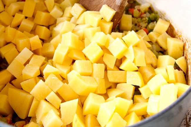 showing how to make potato leek soup by adding potatoes and chicken broth to soup