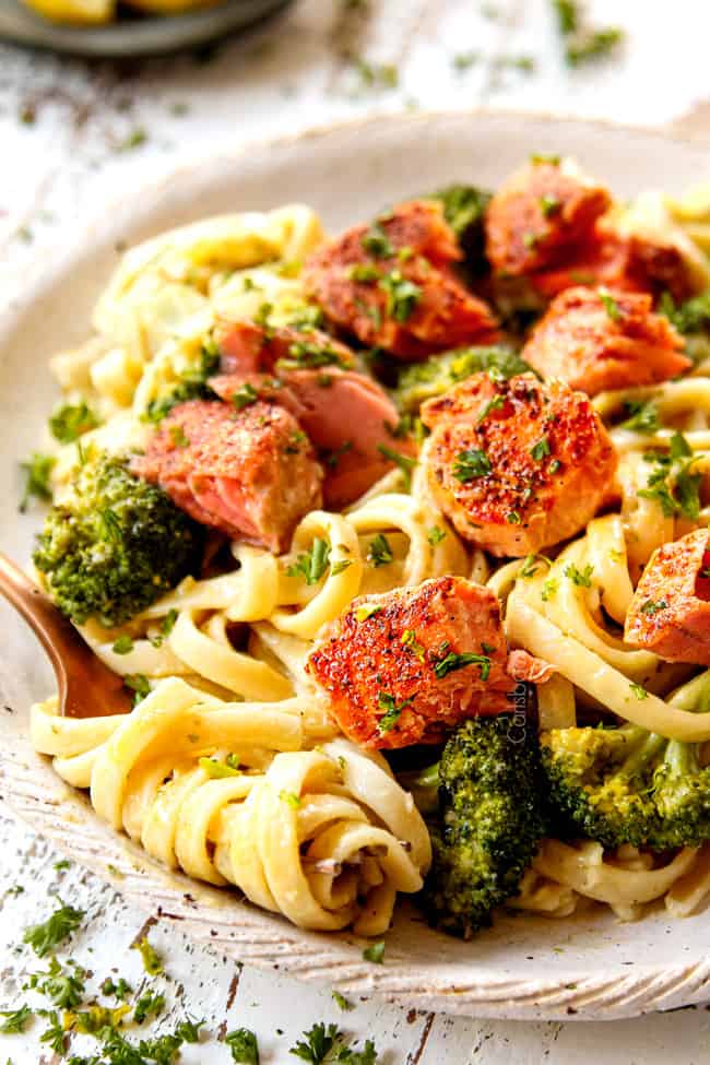 showing how to eat salmon pasta recipe with a fork twirling the creamy pasta