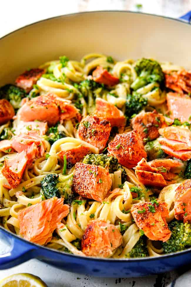 up close of adding salmon to creamy pesto pasta