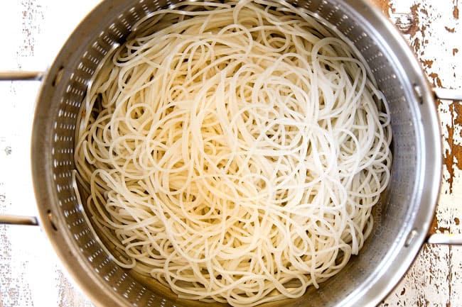 showing how to make Singapore Noodles by draining rice vermicelli in a colander
