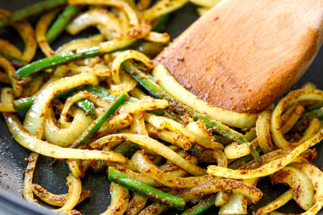 showing how to make Singapore Noodles recipe by stir frying onions, jalapenos and curry powder