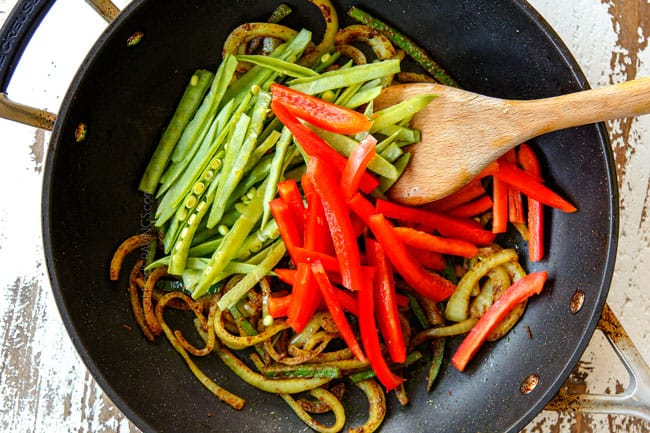showing how to make Singapore Style Noodles by stir frying red bell peppers and snow peas