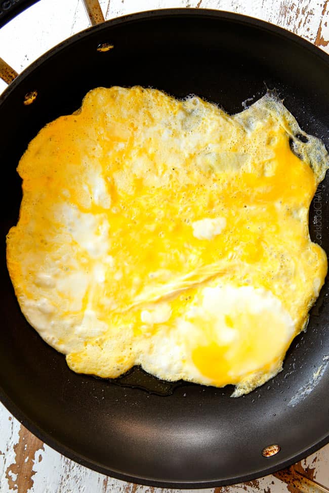 showing how to make Singapore Rice Noodles by cooking eggs flat in a pan until set