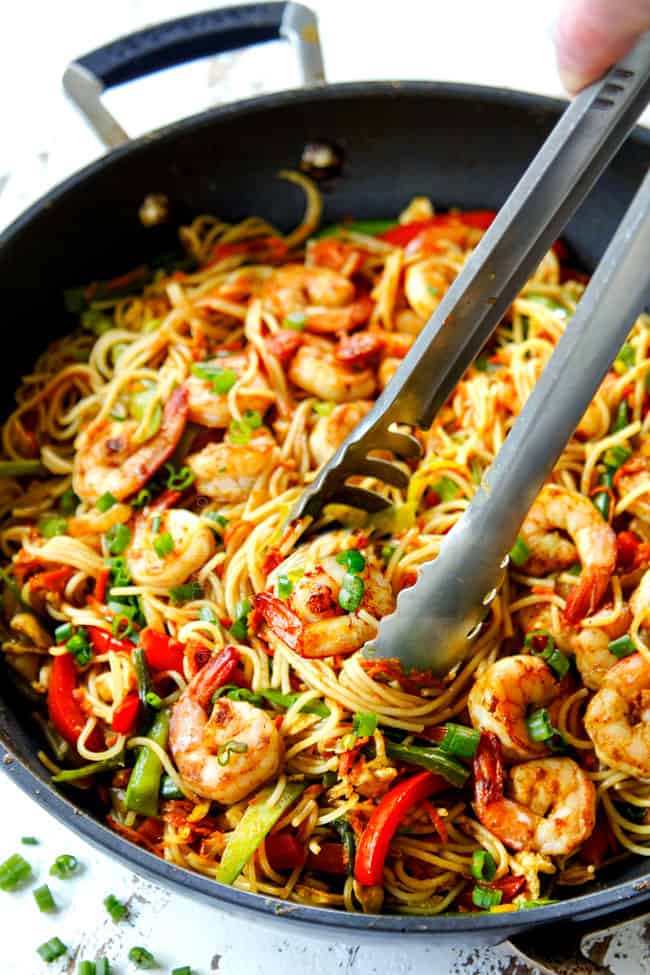 showing how to serve Singapore Noodles recipe by using tongs to pick up noodles