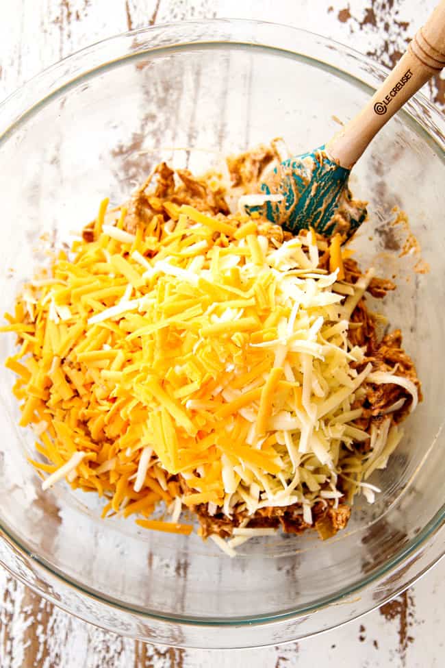 showing how to make chicken enchiladas by adding Monterrey Jack cheese and shredded cheddar cheese to the chicken filling in a glass bowl