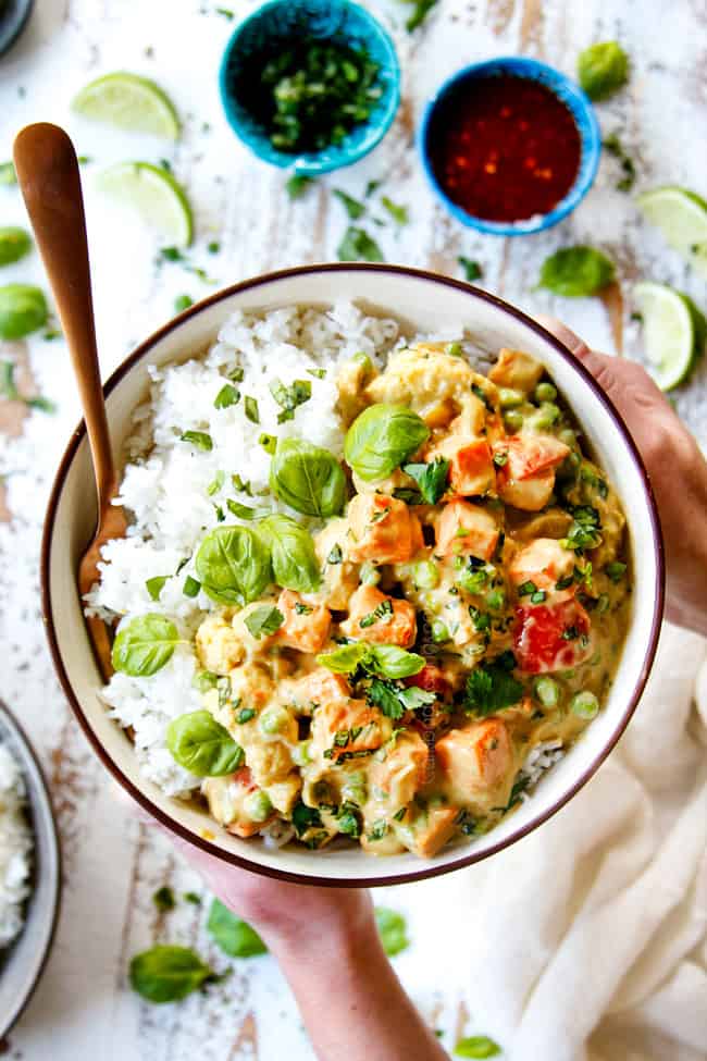 top view of a bowl of Thai Green Curry chicken recipe with rice held held with two hands