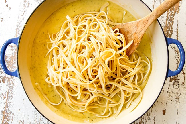 showing how to make salmon pasta by adding pasta to sauce followed by salmon