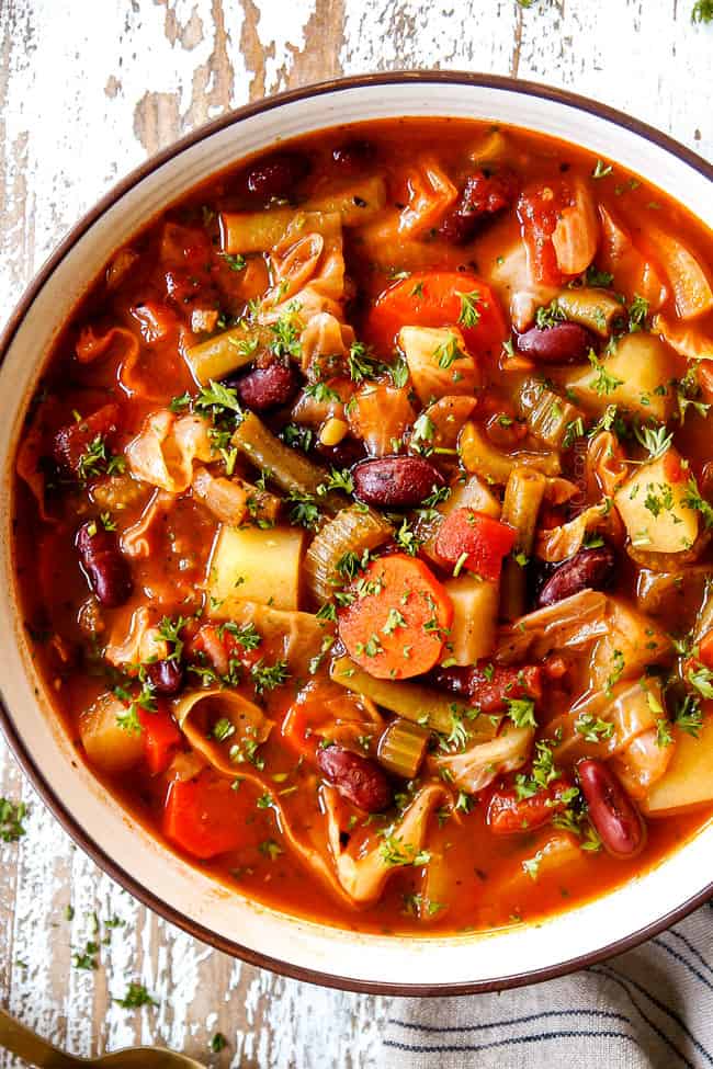 showing how to garnish vegetarian Cabbage Soup recipe by adding fresh parsley to a bowl of soup