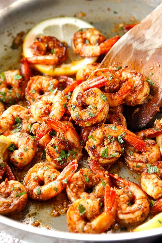 showing how to cook shrimp by tossing lemon garlic shrimp with fresh herbs after cooking