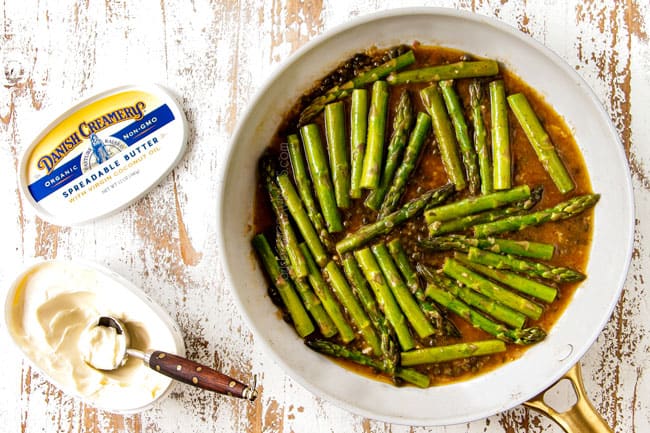showing how to make lemon salmon and asparagus by adding asparagus to lemon sauce
