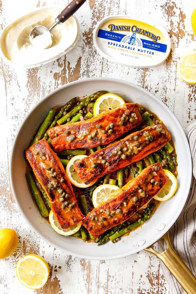 showing how to make lemon butter salmon and asparagus with a top view of salmon laying over asparagus in a pan