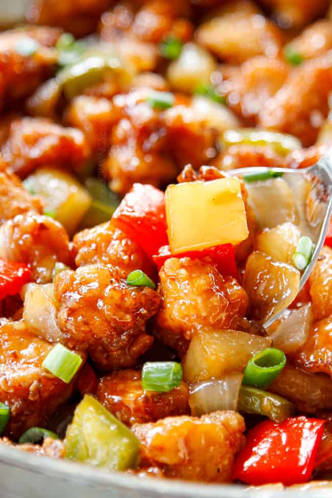 showing how to make Chinese Sweet and Sour Chicken by stirring chicken, pineapple and peppers