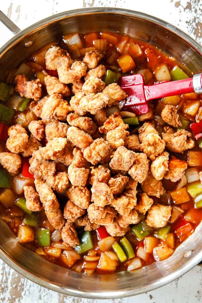 showing how to make sweet and sour chicken by adding breaded chicken to sauce