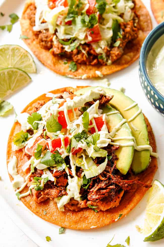 showing how to serve chicken tostadas by making a toppings bar cheese, lettuce, tomatoes, guacamole and sour cream