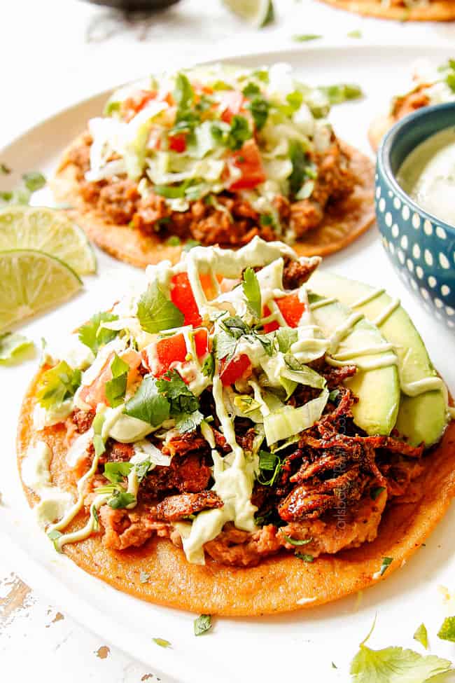 showing how to make chicken tostadas by adding chicken tostada shells over beans