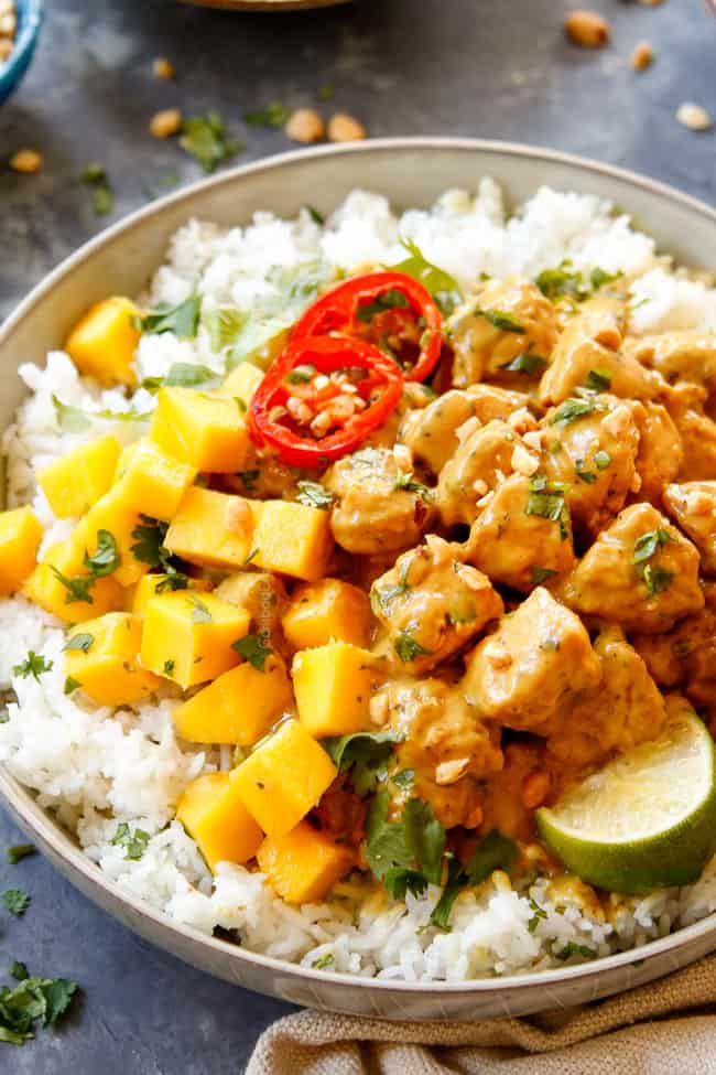 up close of Peanut Butter Sauce Chicken in a bowl with cilantro and mango