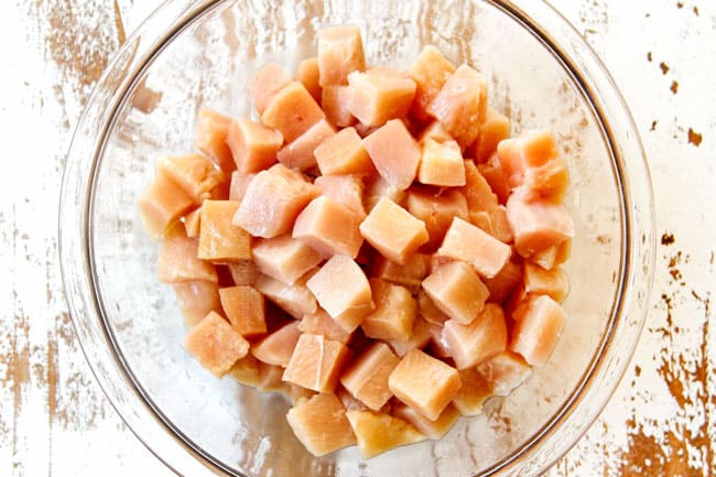 showing how make KFC Popcorn Chicken by chopping chicken into uniform pieces and adding to a bowl