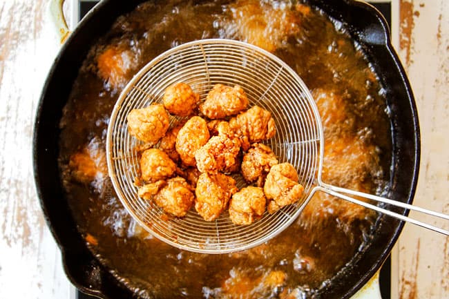 showing how to make KFC Popcorn Chicken by frying chicken until golden them removing with a strainer