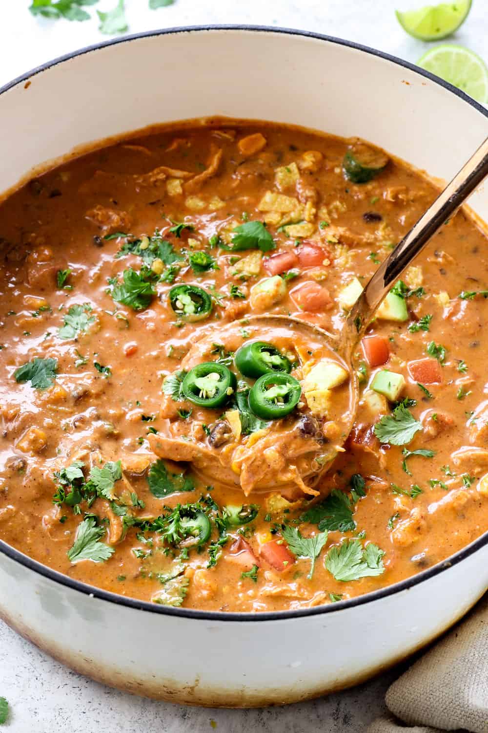 showing how to serve cheesy Chicken Enchilada Soup by stirring cilantro into the soup