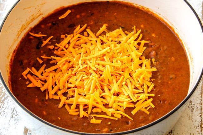 showing how to make cheesy Chicken Enchilada Soup by adding cheddar cheese to soup