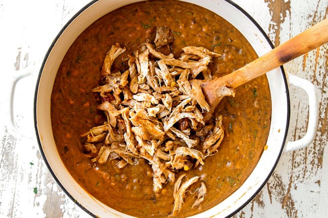 Showing how to make cheesy Chicken Enchilada Soup stirring shredded chicken back into soup.