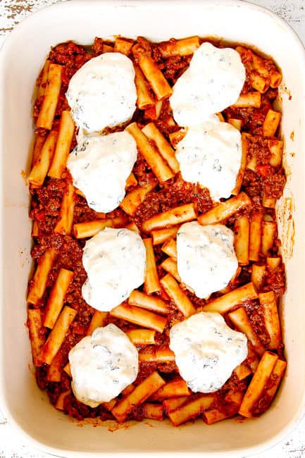 showing how to make Baked Ziti by recipe layering a 9x13 baking dish with ziti mixed with meat sauce followed by ricotta