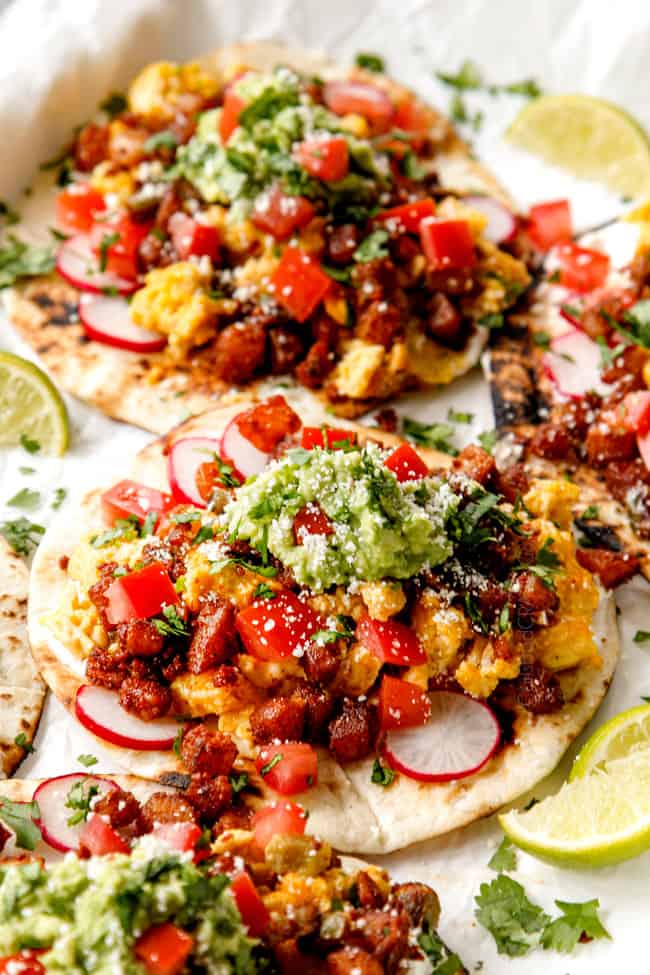 showing how to make breakfast tacos by layering a flour tortilla with sour cream, chorizo, scrambled eggs and potatoes