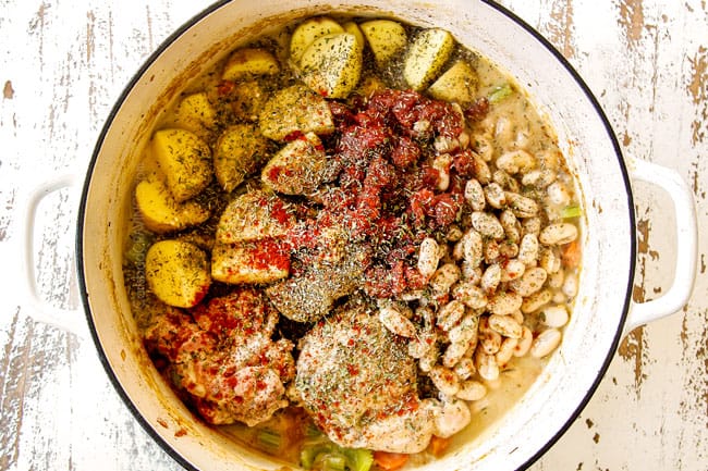 showing how to make chicken stew recipe by adding potatoes, beans fire roasted diced tomatoes, chicken broth and Italian seasonings to the white Dutch oven with the seared chicken