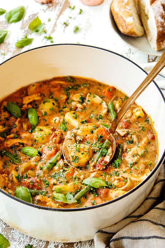 showing how to garnish chicken stew recipe by adding fresh parsley to a big white pot of stew with a copper ladle