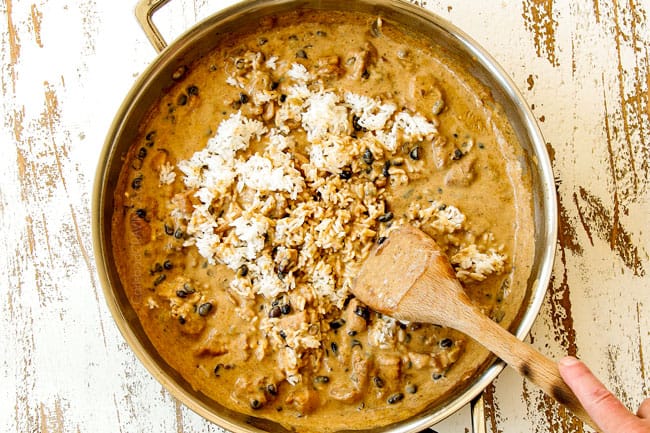 showing how to make Green Chili Chicken recipe by stirring cooked rice into the green chili sauce in a stainless steel skillet