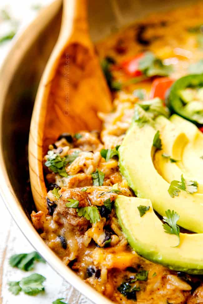 up close showing how to serve Green Chili Chicken and rice by scooping it up with a wood spoon