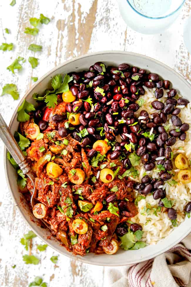showing how to serve Ropa Vieja recipe by adding to a bowl with rice and beans and garnishing with cilantro
