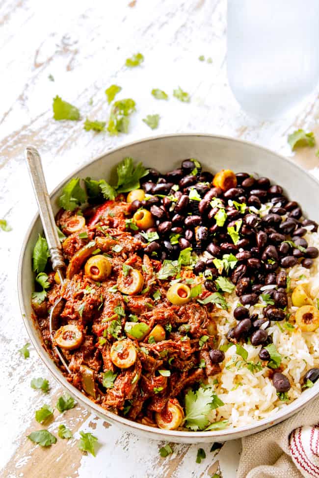 showing how to garish Cuban Ropa Vieja by adding cilantro and more Spanish olives to beef in a bowl with rice