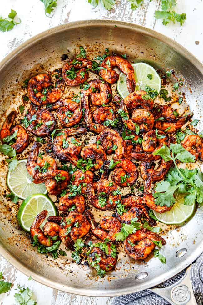 showing how to make jerk shrimp by cooking shrimp in a skillet and garnishing with parsley
