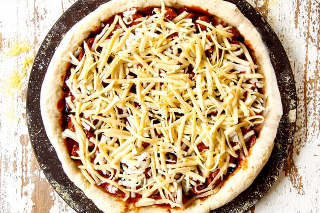 showing how to make BBQ Chicken Pizza recipe by topping pizza with mozzarella cheese and Gouda