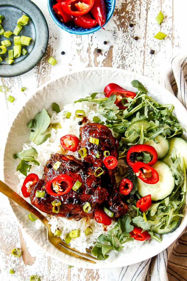 showing how to make Filipino Chicken Adobo by serving over white rice and garnishing with green onions