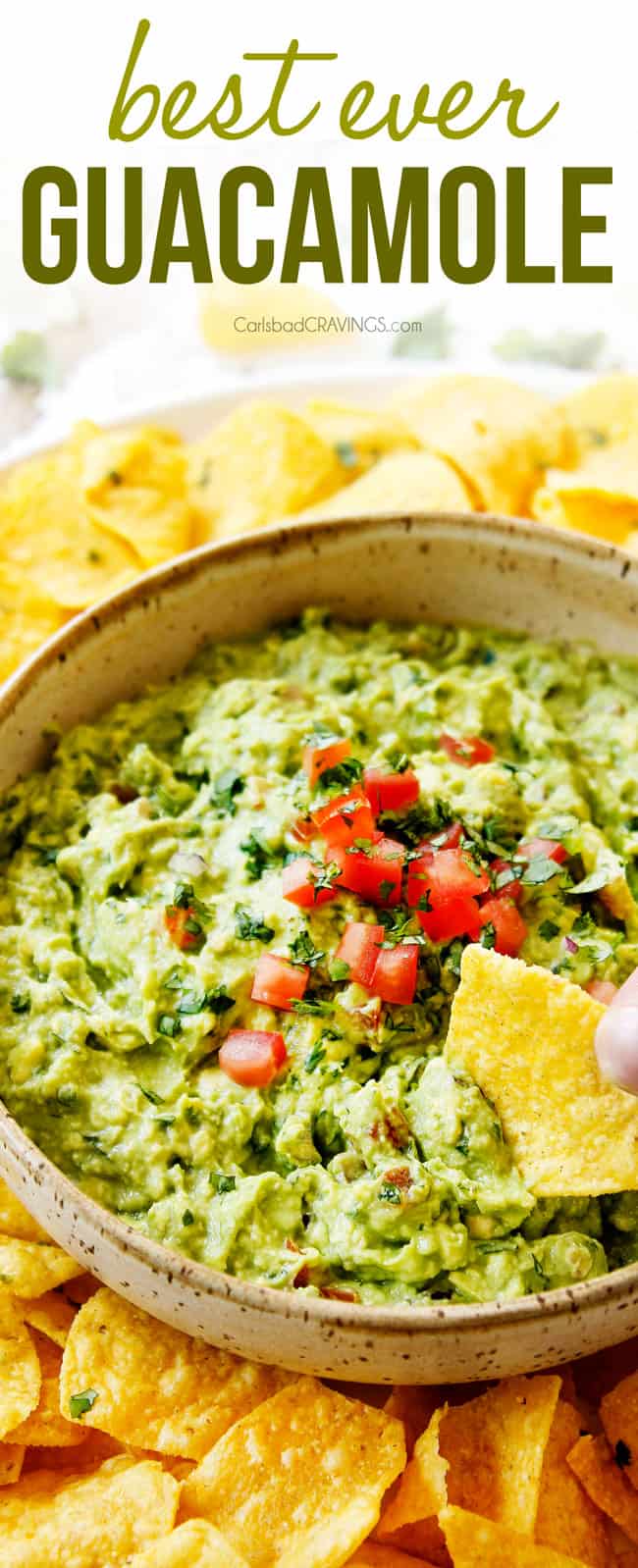 showing how to eat homemade guacamole by dipping  a chip into the guacamole in  a tan bowl surrounded by tortilla chips