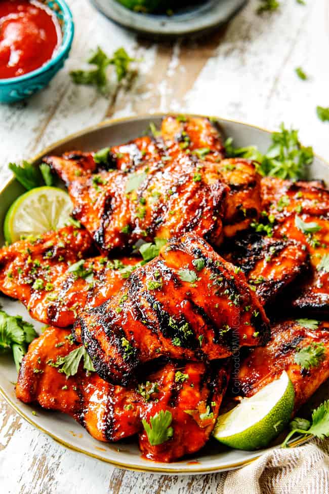 Honey Sriracha Chicken recipe with grill marks on a grey plate with limes