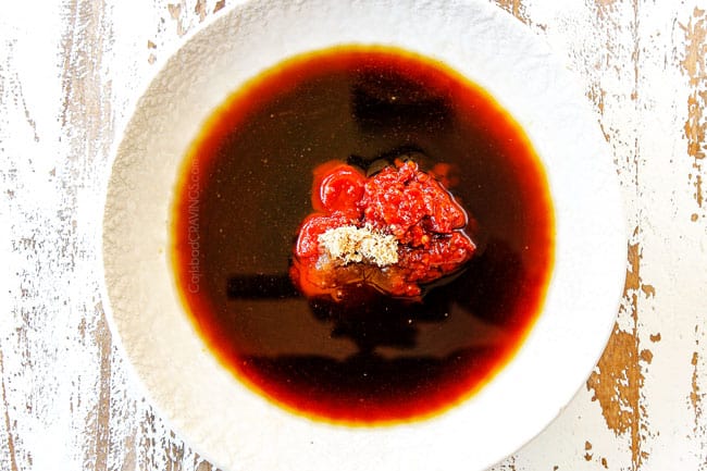 showing how to make Hunan chicken by whisking together Hunan sauce ingredients: soy sauce, oyster sauce, chili bean sauce, ketchup and rice wine