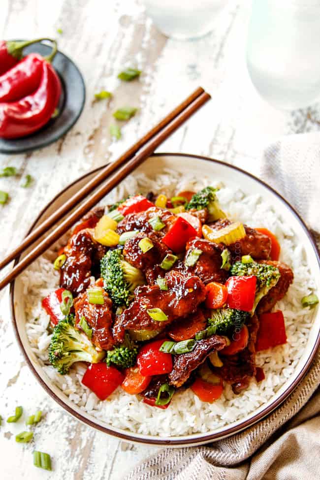 showing how to serve Hunan Chicken by placing over a bowl of rice with chopsticks