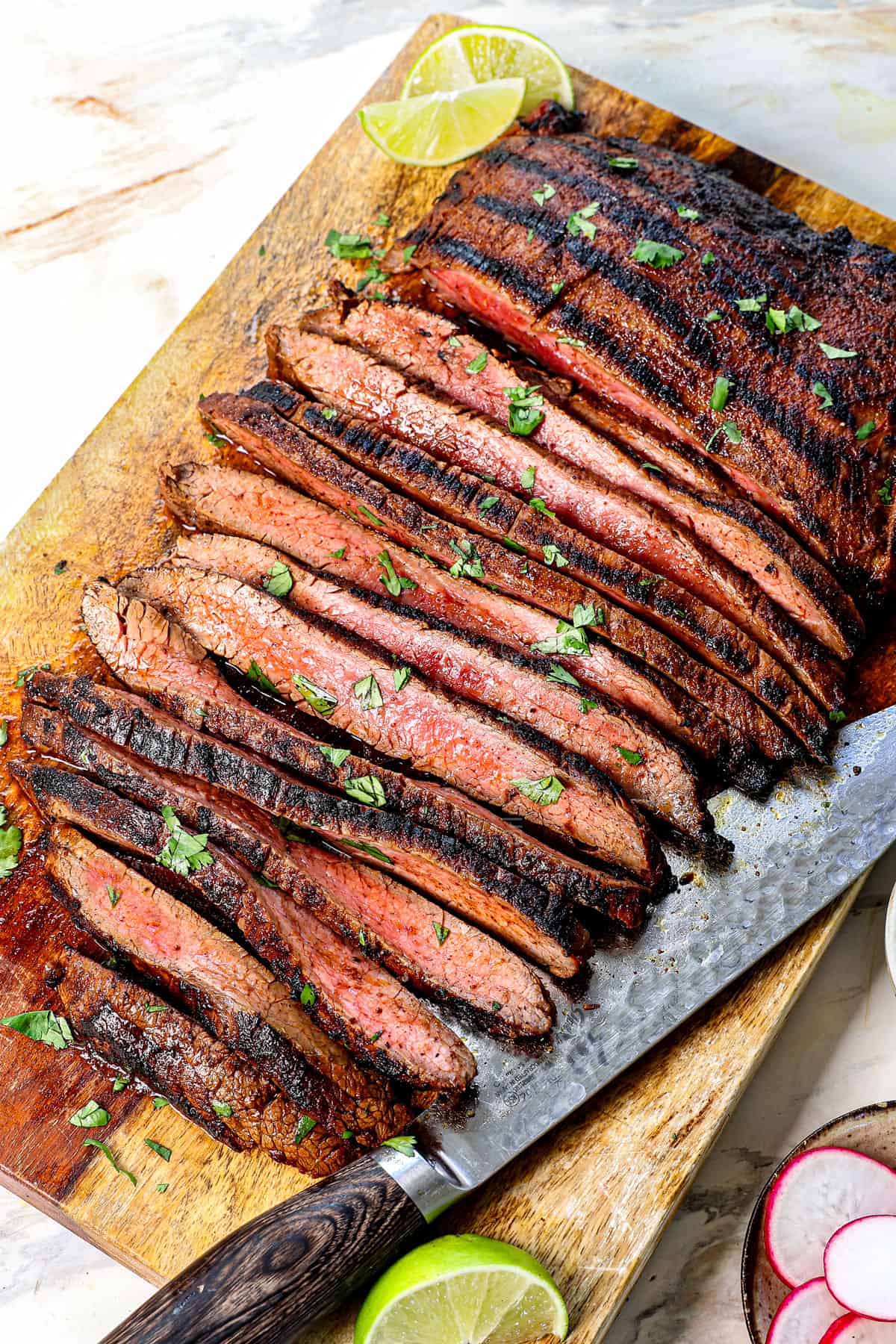 carne asada recipe on a cutting board cut into slices showing how thin to cut it