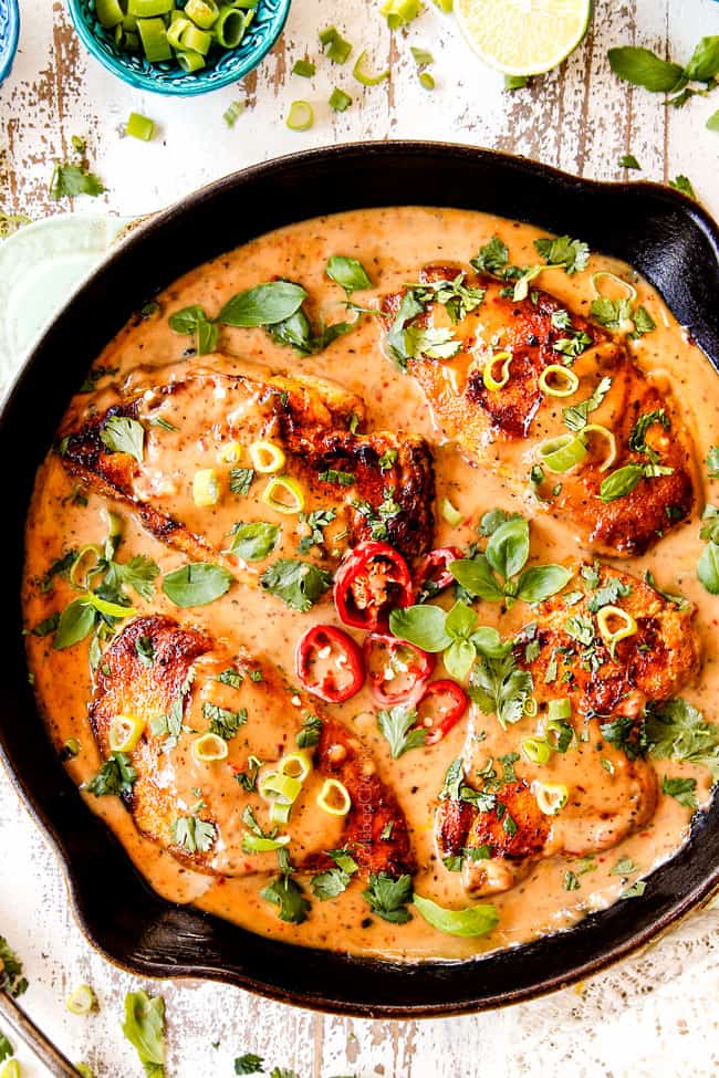 top view of a coconut milk chicken in creamy coconut milk sauce in a cast iron skillet