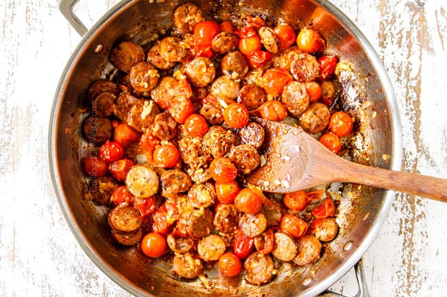 showing how to make spinach pasta by cooking sausage and tomatoes together in a stainless steal skillet