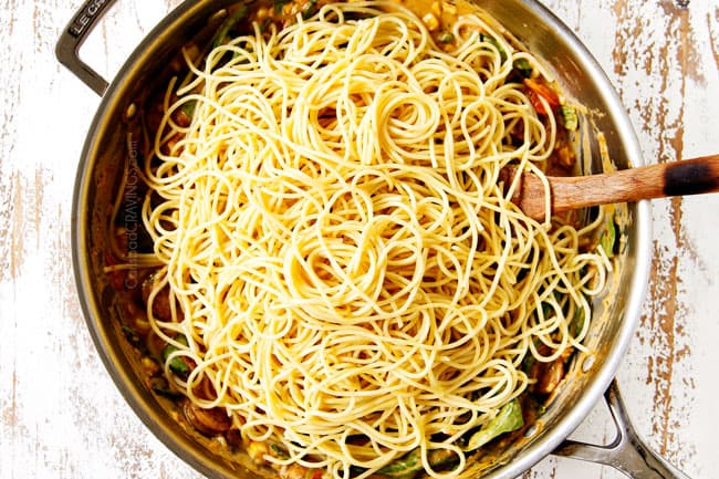 showing how to make spinach pasta by adding spaghetti to cream sauce in stainless steel skillet