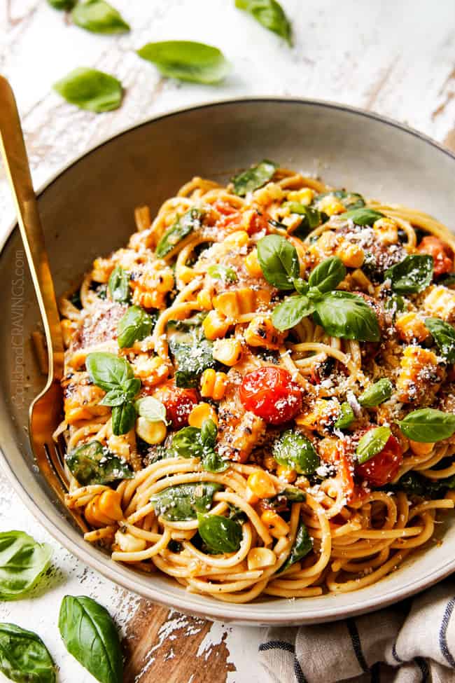 side view of a grey bowl of spinach pasta recipe garnished with Parmesan