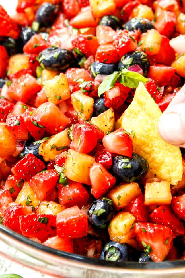 up close showing how to eat strawberry salsa by scooping it up with a tortilla chip